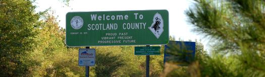 The Welcome to Scotland County sign with trees around it